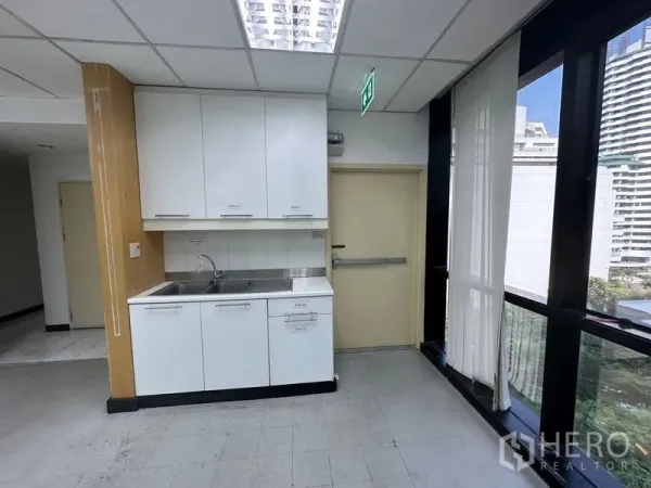 Office Space for rent in Khlong Toei, Bangkok - Office pantry with sink and white cabinets beside large windows.