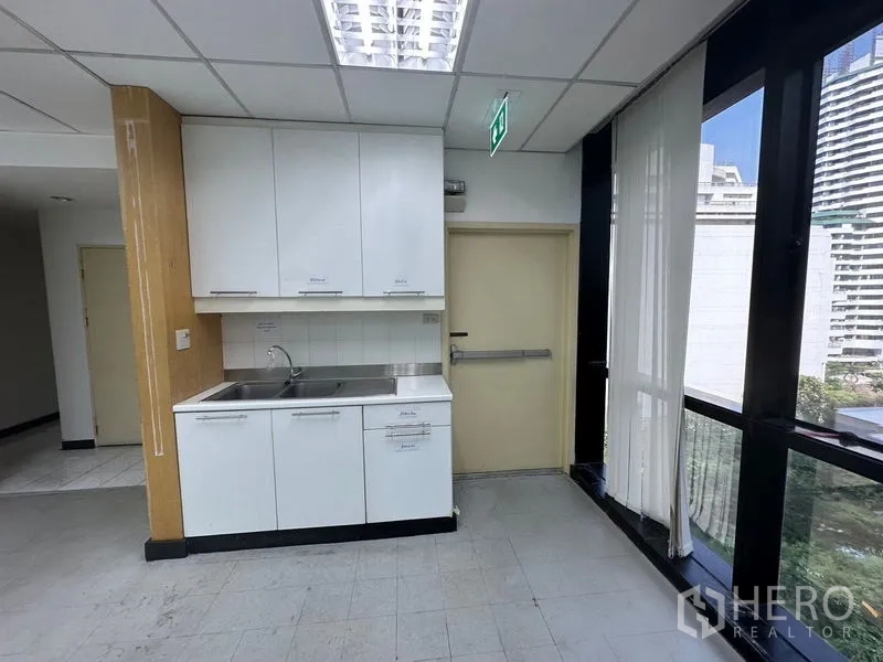 Office Space for rent in Khlong Toei, Bangkok - Office pantry with sink and white cabinets beside large windows.