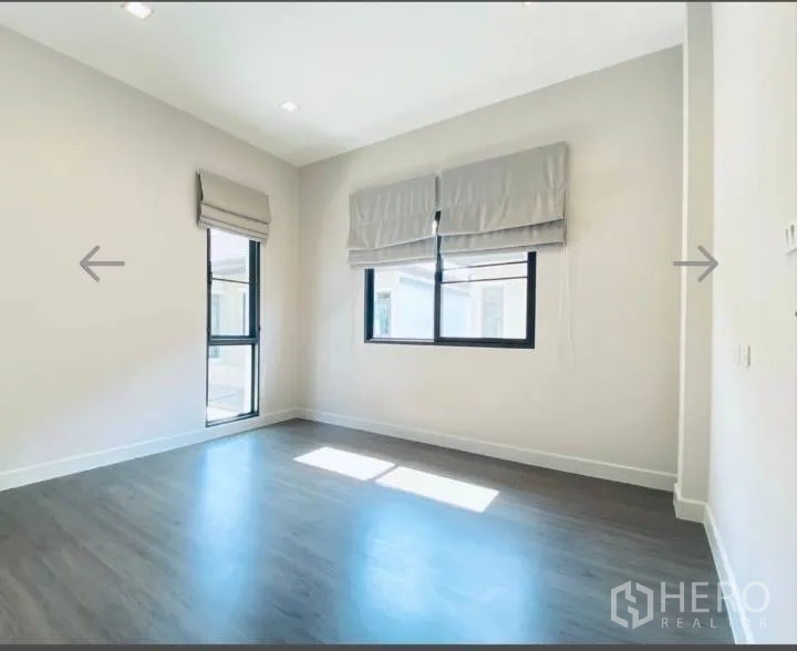 Detached House for sale in Saphan Sung, Bangkok - Bright secondary bedroom with two windows and wood floors.