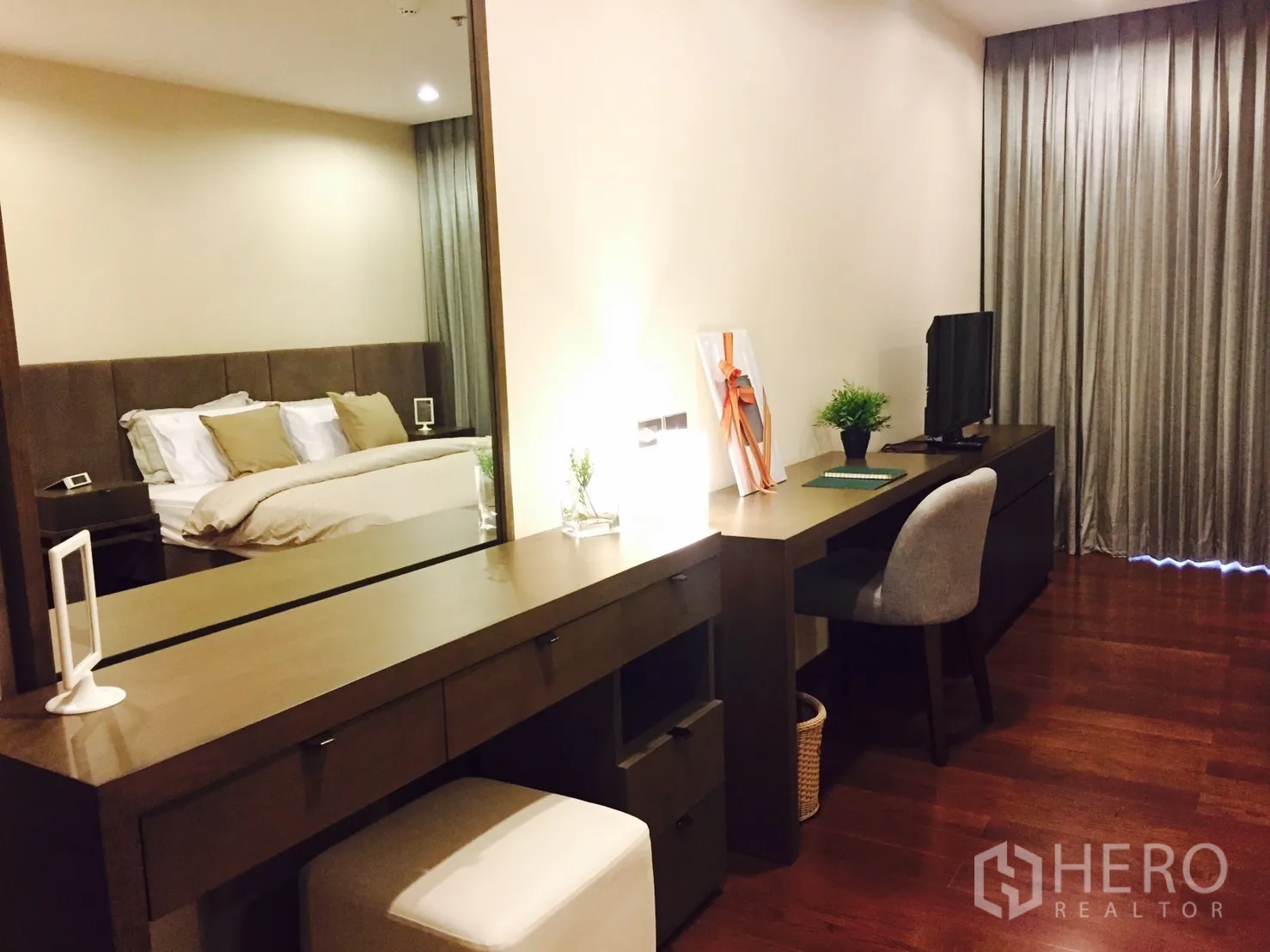 公寓 出租或出售在Sathon, Bangkok - 主卧内的妆台与长书桌，配镜面、电视与座椅。