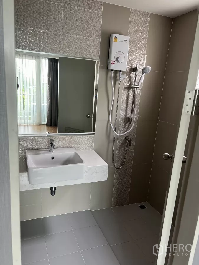 Detached House for rent or sale in Don Mueang, Bangkok - Shower room with mosaic accent wall, water heater, basin and mirror.