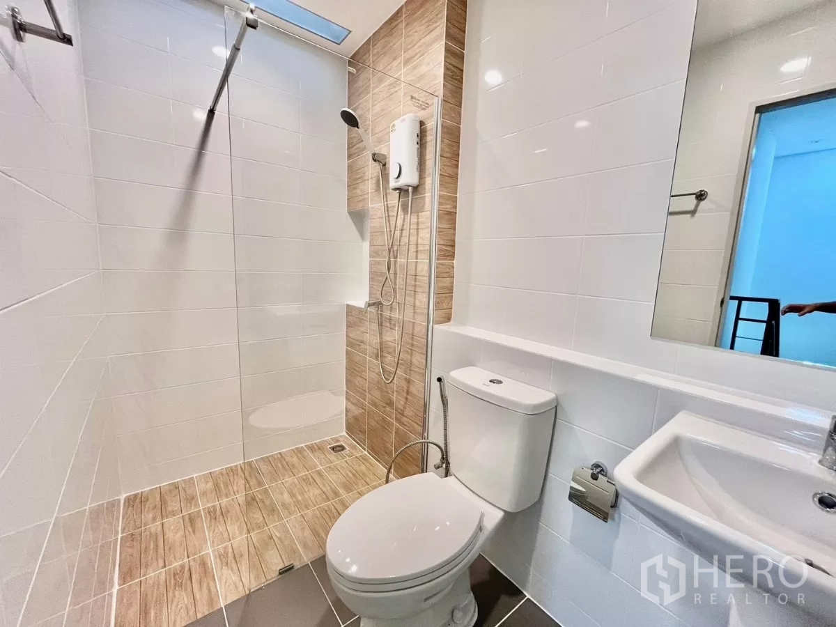 Townhouse for rent in Bang Phli, Samut Prakan - Modern bathroom with glass-enclosed shower, white wall tiles, and handheld shower set.