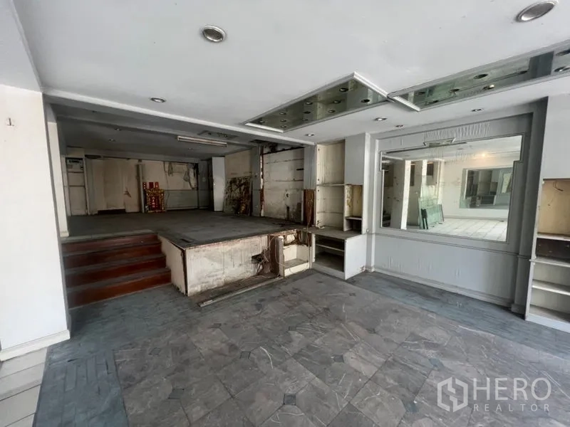 零售空间 出租在Watthana, Bangkok - 店面前区带抬高平台、展示架与筒灯。