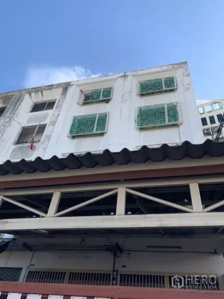 店屋 出租在Suan Luang, Bangkok - 多层店屋白色外立面，绿色窗格，蓝天下的正面视角