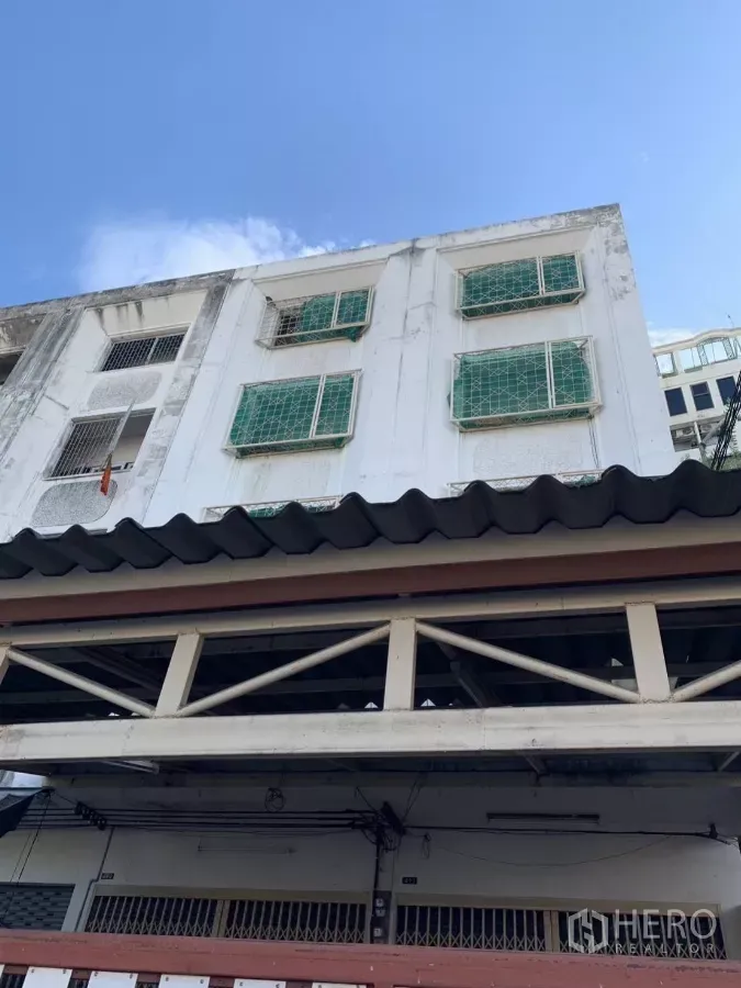 อาคารพาณิชย์ ให้เช่าในSuan Luang, Bangkok - ด้านหน้าอาคารพาณิชย์หลายชั้น สีขาว มีเหล็กดัดหน้าต่างสีเขียว ใต้ท้องฟ้าแจ่มใส