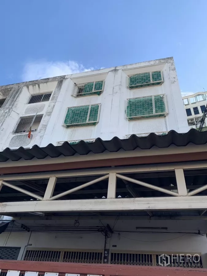 อาคารพาณิชย์ ให้เช่าในSuan Luang, Bangkok - ด้านหน้าอาคารพาณิชย์หลายชั้น สีขาว มีเหล็กดัดหน้าต่างสีเขียว ใต้ท้องฟ้าแจ่มใส