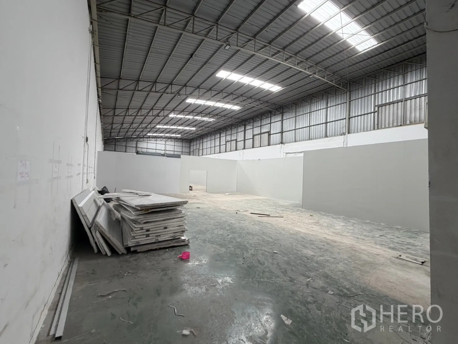 Warehouse for rent in Khlong Luang, Pathum Thani - Wide aisle along partition walls with stacked materials against the side wall.