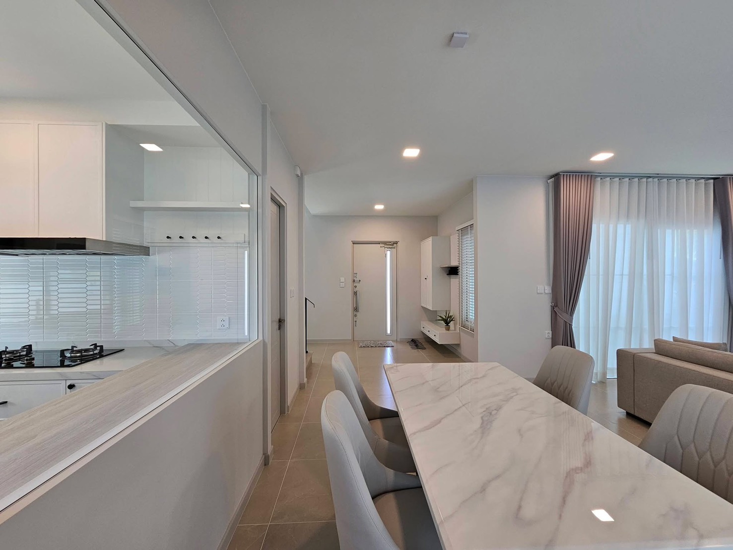 Detached House for rent in Bang Phli, Samut Prakan - Open-plan dining area beside a glass-partition kitchen with a marble-top table.