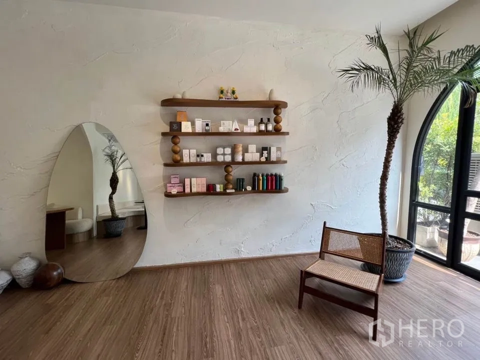 零售空间 出租在Watthana, Bangkok - 陈列角落设悬浮木架、肌理墙、拱形窗与藤编椅。