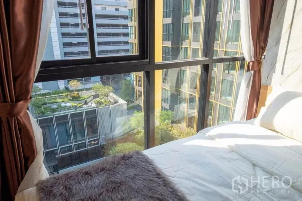 คอนโด ให้เช่าในBang Na, Bangkok - มุมห้องนอนพร้อมหน้าต่างเต็มบาน มองเห็นสวนส่วนกลางและอาคารโมเดิร์น
