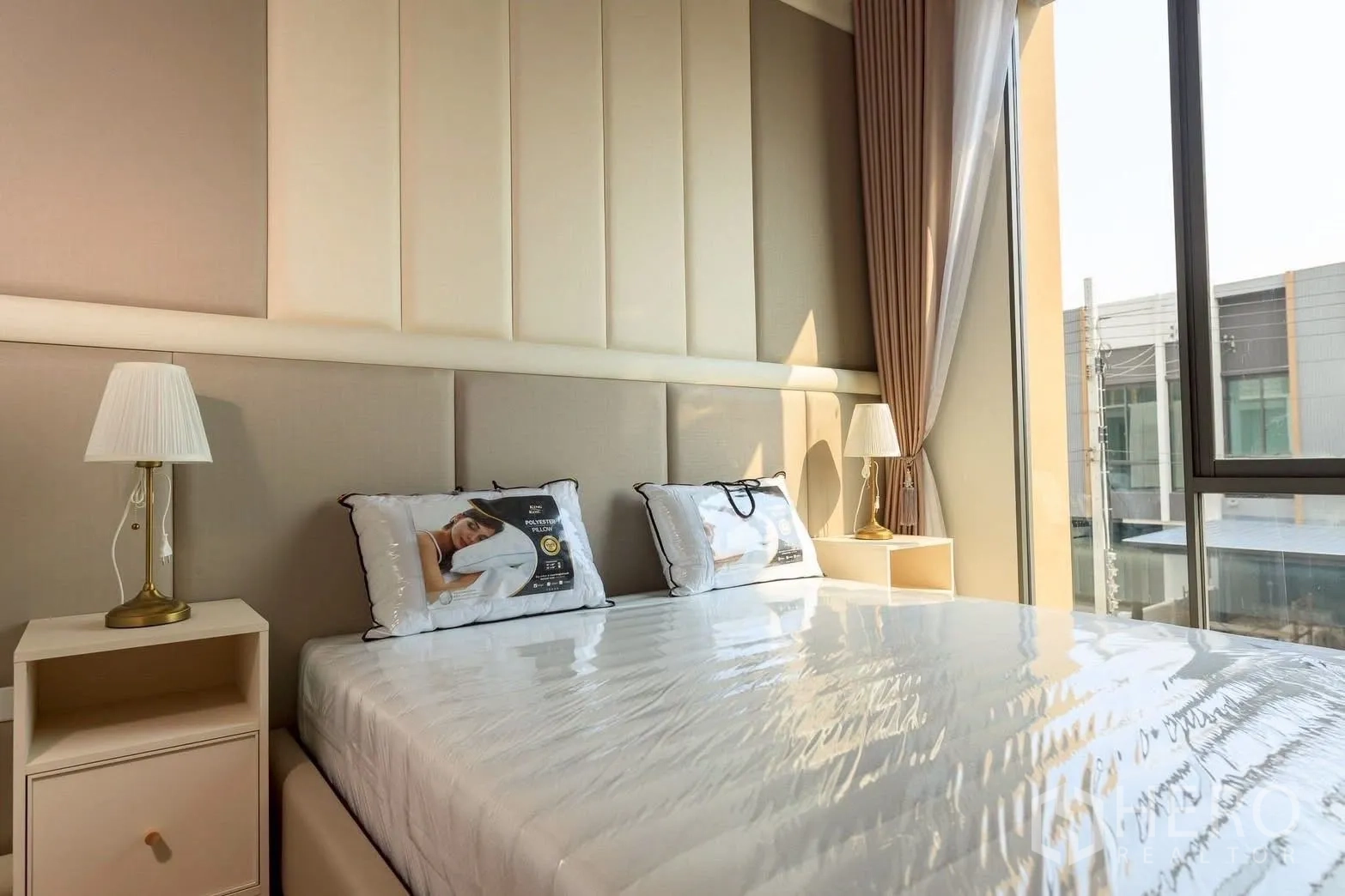 Townhouse for rent or sale in Bang Phli, Samut Prakan - Bright bedroom with upholstered headboard and expansive window overlooking the neighborhood.