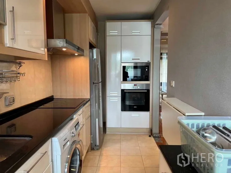 公寓 出租或出售在Watthana, Bangkok - 走廊式厨房，内置烤箱和微波炉，灶台、油烟机、冰箱与洗衣机