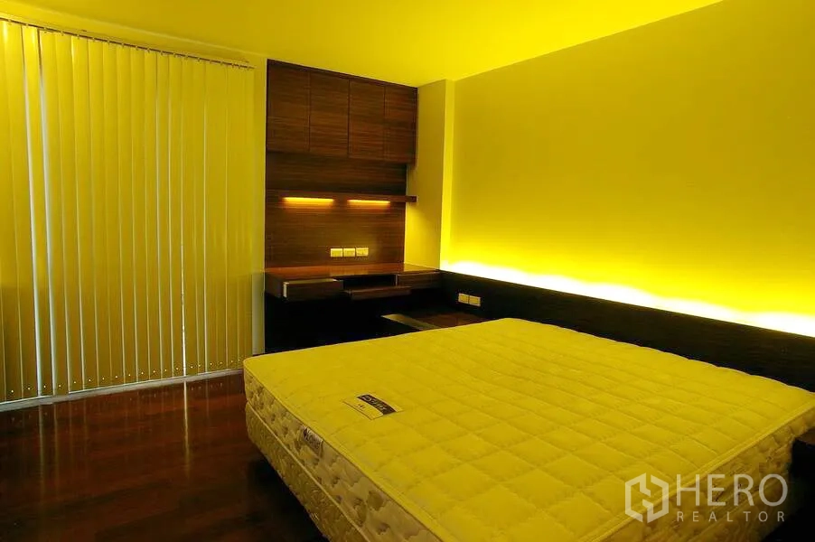 公寓 出租在Watthana, Bangkok - 卧室配暖色背光、木质书桌与置物架、竖百叶窗和床垫。