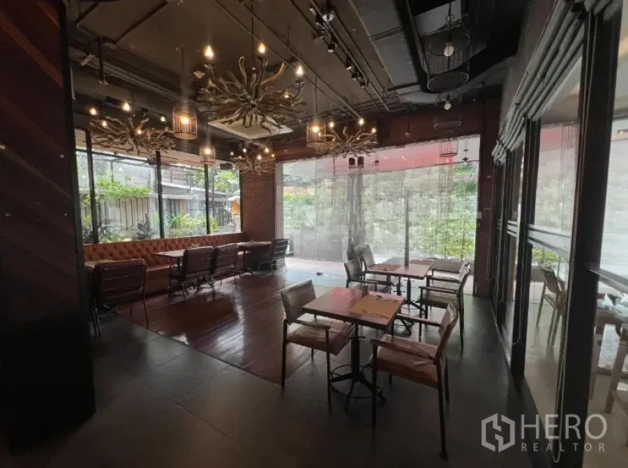 พื้นที่ขายปลีก ให้เช่าในWatthana, Bangkok - ห้องรับประทานอาหารของร้าน มีเบาะยาวหนัง โต๊ะไม้ โคมไฟระย้า และกระจกเต็มผนังมองเห็นต้นไม้
