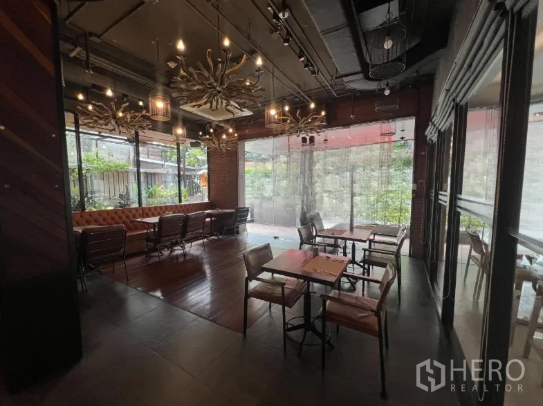พื้นที่ขายปลีก ให้เช่าในWatthana, Bangkok - ห้องรับประทานอาหารของร้าน มีเบาะยาวหนัง โต๊ะไม้ โคมไฟระย้า และกระจกเต็มผนังมองเห็นต้นไม้