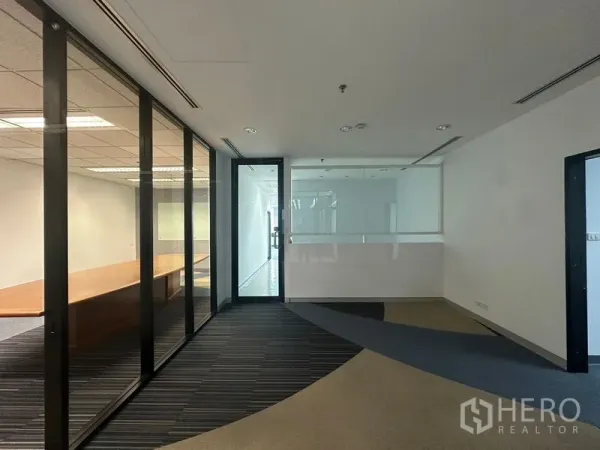 Office Space for rent in Khlong Toei, Bangkok - Entrance corridor with glass partitions leading to a boardroom and striped carpet flooring in a Bangkok office.