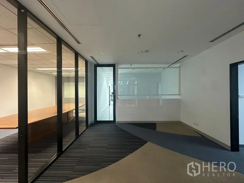 Office Space for rent in Khlong Toei, Bangkok - Entrance corridor with glass partitions leading to a boardroom and striped carpet flooring in a Bangkok office.