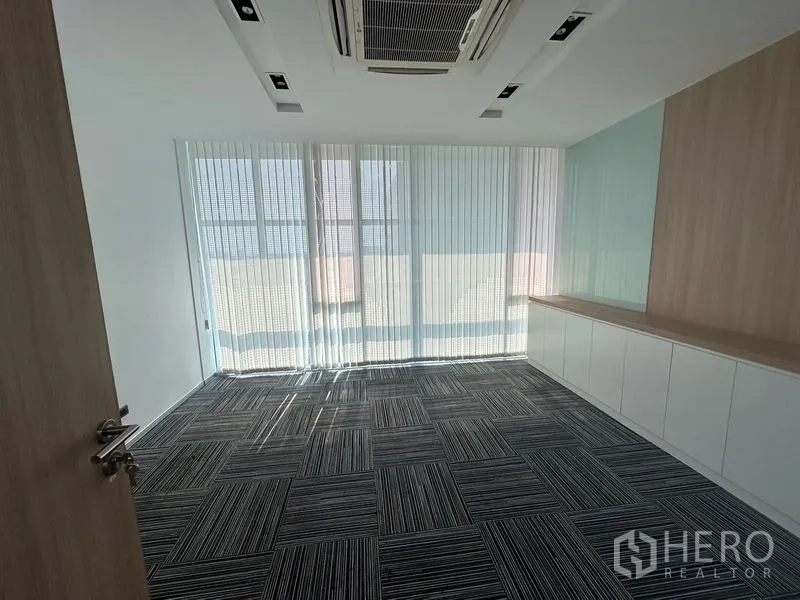 Office Space for rent - Bright multipurpose room with patterned carpet tiles, built-in cabinets, and tall windows.
