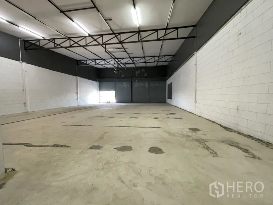 คลังสินค้า ให้เช่าในLam Luk Ka, Pathum Thani - พื้นที่โกดังโปร่ง เพดานสูง โครงเหล็ก ไฟสว่าง และประตูม้วนด้านหน้า.