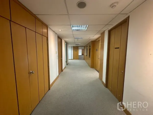 Office Space for rent in Khlong Toei, Bangkok - Carpeted corridor on an office floor with wood-paneled doors and recessed ceiling lights.