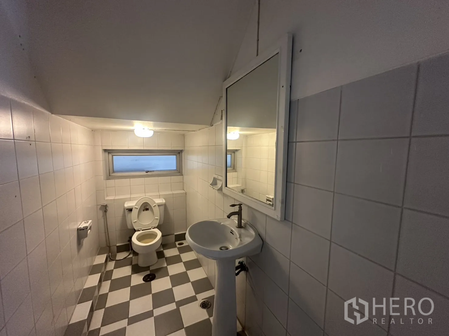 Home Office for rent in Watthana, Bangkok - Compact restroom with checkered tiles, sink, and toilet.