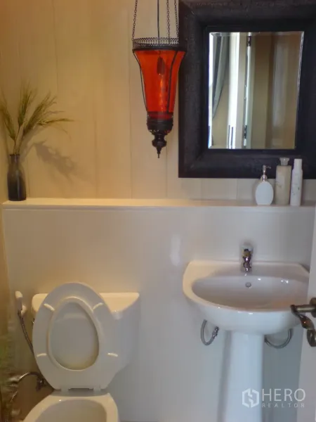 Condominium for rent in Khlong Toei, Bangkok - Clean guest bathroom with pedestal sink, mirror and red pendant lantern.