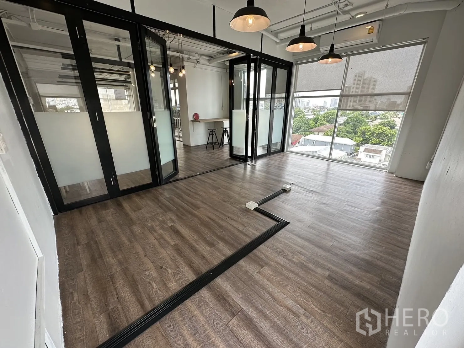 ออฟฟิศ for rent in Watthana, Bangkok - มุมทำงานมีห้องประชุมกั้นกระจก โคมไฟแขวน ม่านม้วน และหน้าต่างกว้างมองเห็นวิวชุมชน