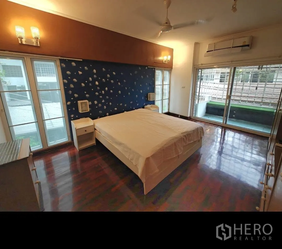 Condominium for rent in Sathon, Bangkok - Bedroom with large bed, wood flooring, ceiling fan, air conditioning, and balcony access.