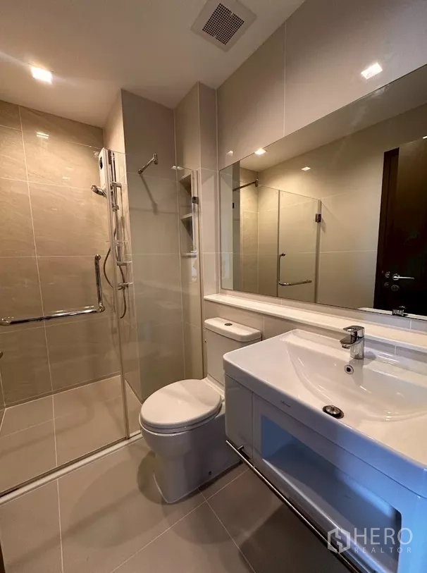 Condominium for rent in Chatuchak, Bangkok - Modern bathroom with glass shower, vanity and toilet.