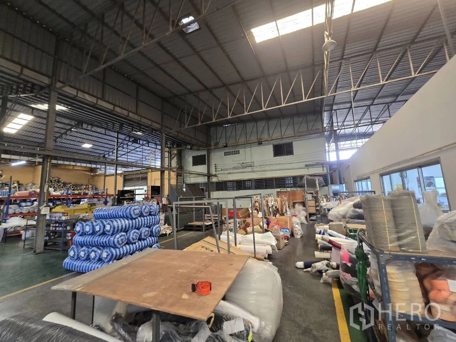 Factory for rent in Sam Phran, Nakhon Pathom - Warehouse zone with stacked fabric rolls and a mezzanine structure.