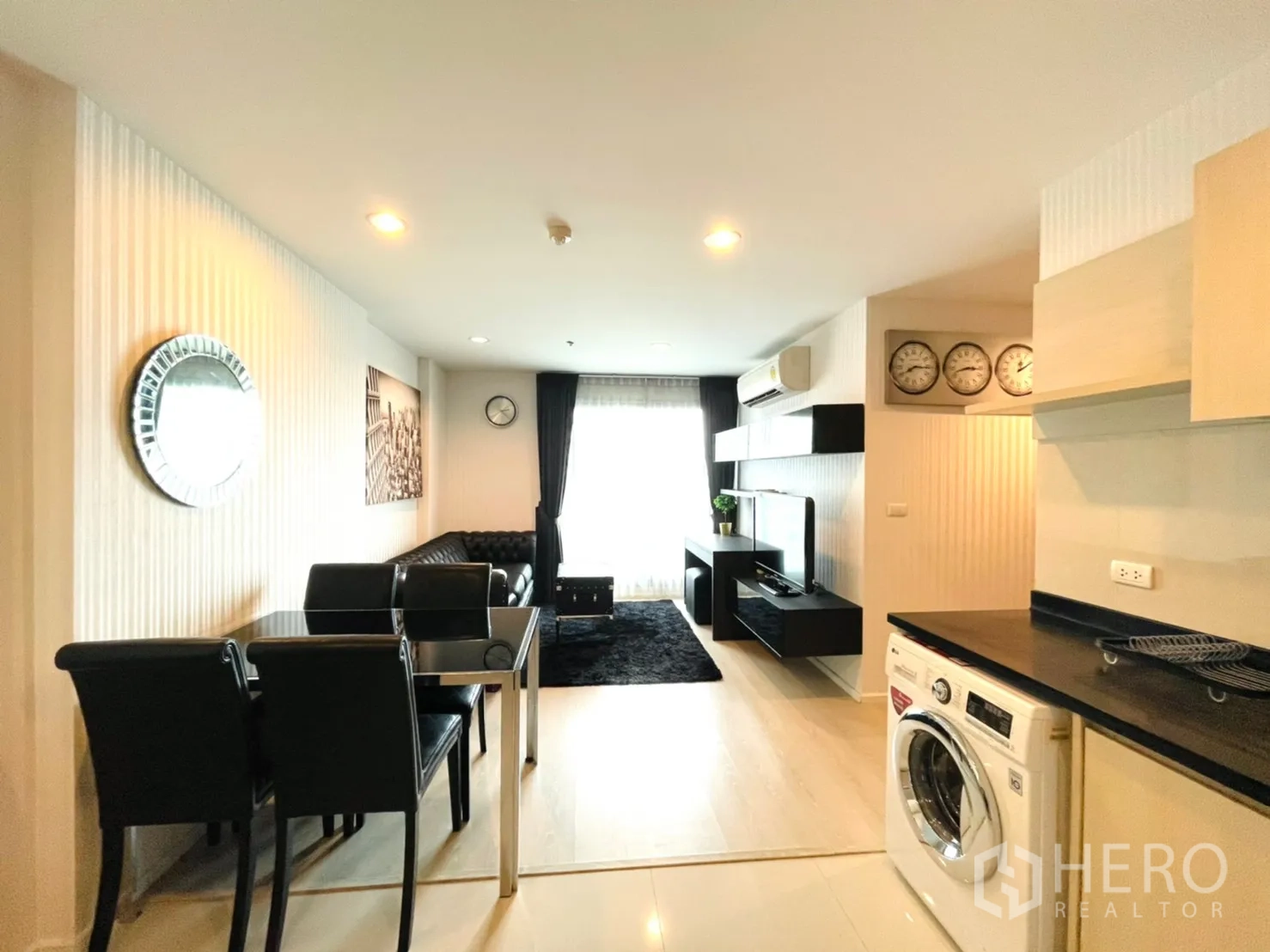 Condominium for sale in Sathon, Bangkok - Bright lounge with dining set, TV unit, balcony window and kitchen corner featuring a washing machine.