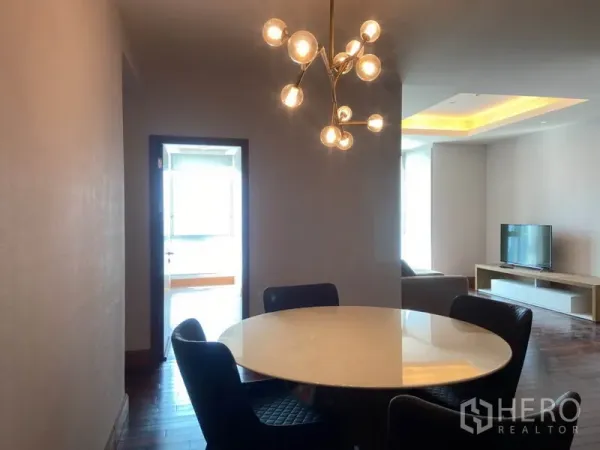 公寓 出租在Sathon, Bangkok - 餐区配圆桌与艺术吊灯，与客厅相连的开放式布局。
