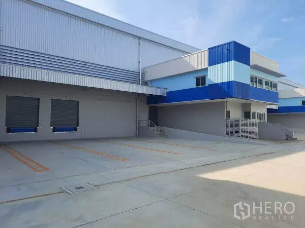 工厂 出租在Bang Lamung, Chon Buri - 现代自由区仓库外立面，蓝色办公楼体与双装卸月台。