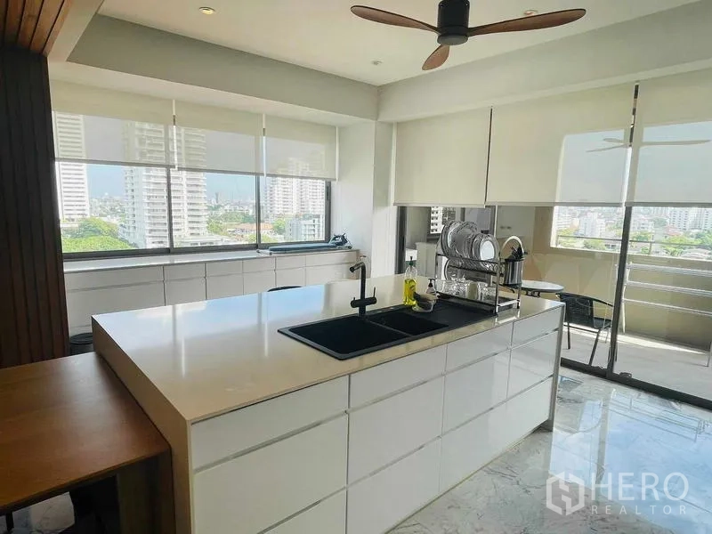 คอนโด ให้เช่าหรือขายในWatthana, Bangkok - ครัวสว่างไอแลนด์สีขนาดใหญ่ อ่างล้างสีดำ และหน้าต่างรอบด้านเห็นวิวเมือง
