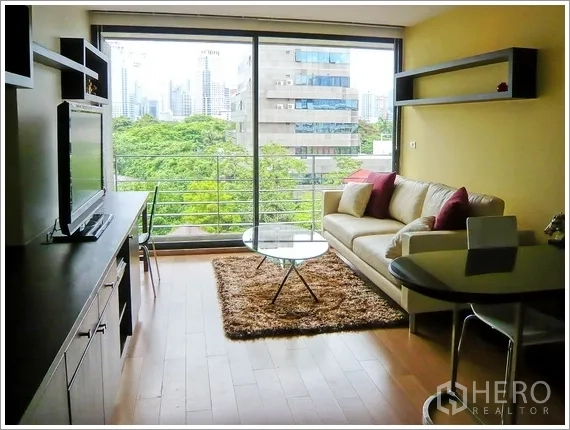 คอนโด ให้เช่าหรือขายในPathum Wan, Bangkok - ห้องนั่งเล่นกระจกเต็มบาน พื้นไม้ ระเบียง วิวสวนและตึกใจกลางเมือง ในคอนโดปทุมวัน