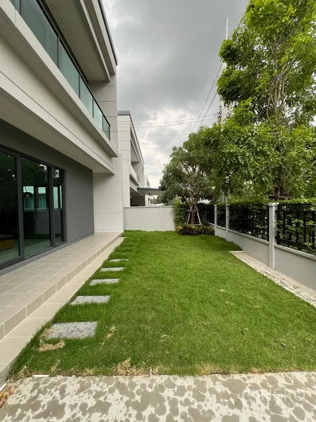 Detached House for rent or sale in Bang Phli, Samut Prakan - Side garden with green lawn, trees and stepping stones along the house.