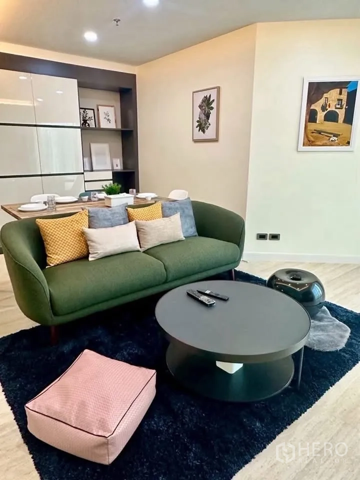 Condominium for rent in Huai Khwang, Bangkok - Stylish lounge setup with green sofa, round table, and pouf.