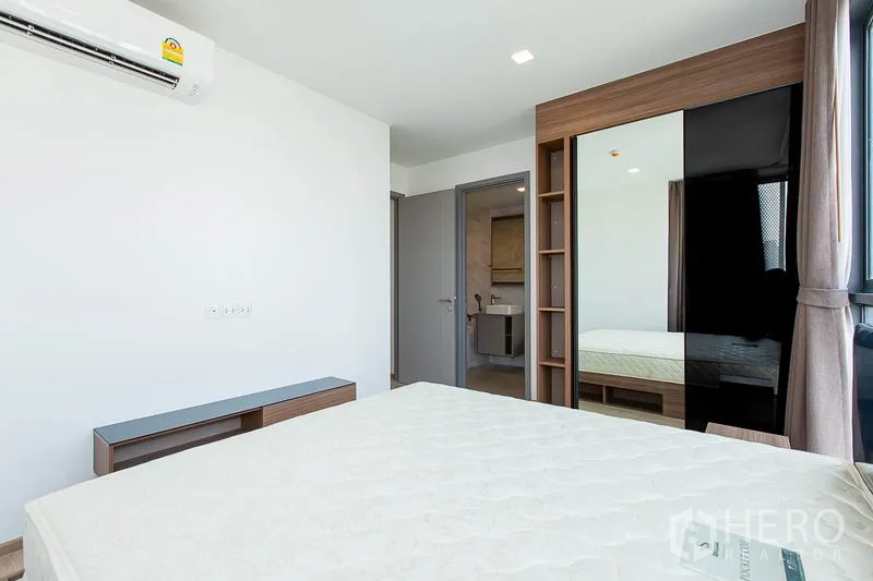 Condominium for rent in Watthana, Bangkok - Bedroom with built-in wardrobe, mirrored sliding doors and ensuite bathroom access.