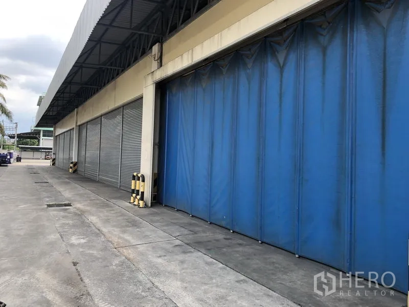Factory for rent in Lam Luk Ka, Pathum Thani - Covered loading bay featuring blue dock curtains and roller shutters across several bays.