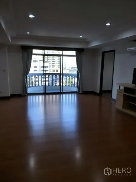 Condominium for rent in Watthana, Bangkok - Lounge opening to a balcony with city views and a classic balustrade railing.
