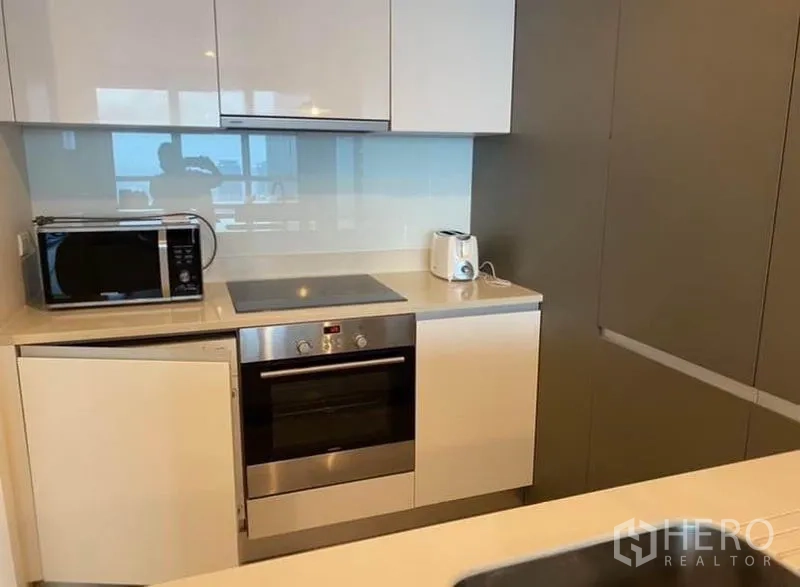 คอนโด ให้เช่าในKhlong San, Bangkok - ภาพใกล้ชิดเตาไฟฟ้าและเตาอบ พร้อมไมโครเวฟและที่ปิ้งขนมปังบนเคาน์เตอร์