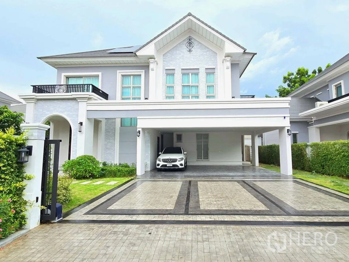Detached House for rent or sale in Bang Phli, Samut Prakan - Grand facade of a luxury two-storey house with expansive driveway and covered parking at dusk.