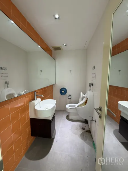 零售空间 出租在Bang Rak, Bangkok - 男卫生间，带洗手盆、镜面、橙色墙砖及小便池和坐便器