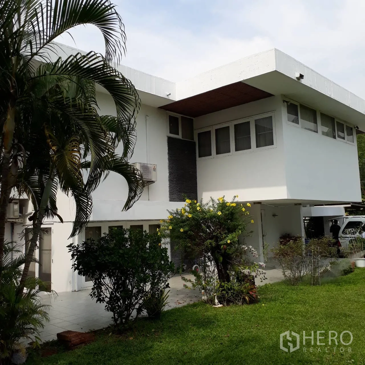 บ้าน ให้เช่าในKhlong Toei, Bangkok - บ้านสองชั้นสีขาวชายคากว้าง ลานกระเบื้อง และสวนทรอปิคัล