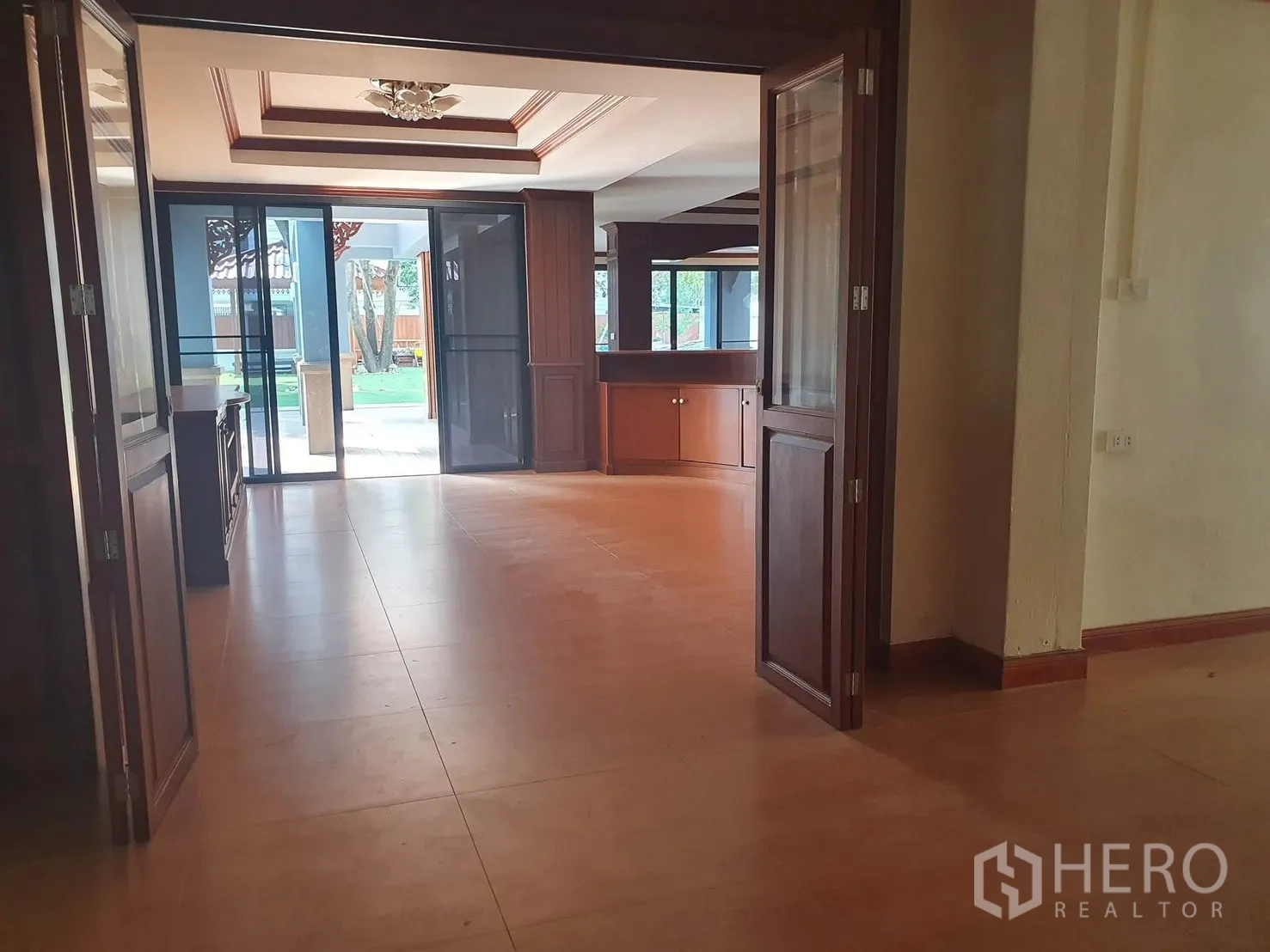 Detached House for rent in Sathon, Bangkok - Open living area with tile floors, wood cabinetry, and sliding glass doors to the garden.