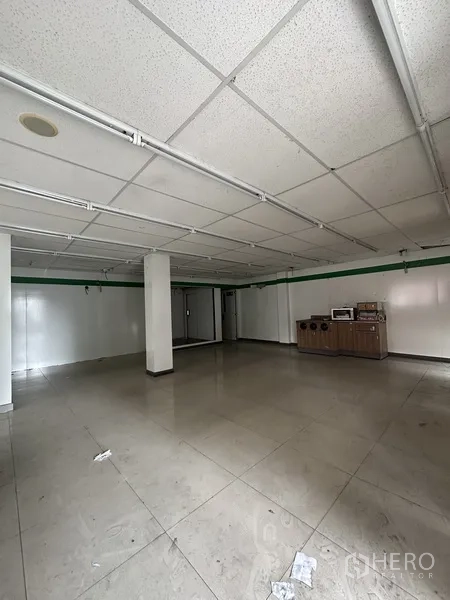 零售空间 出租在Khlong Toei, Bangkok - 宽敞的瓷砖展厅，立柱分区与日光灯照明。