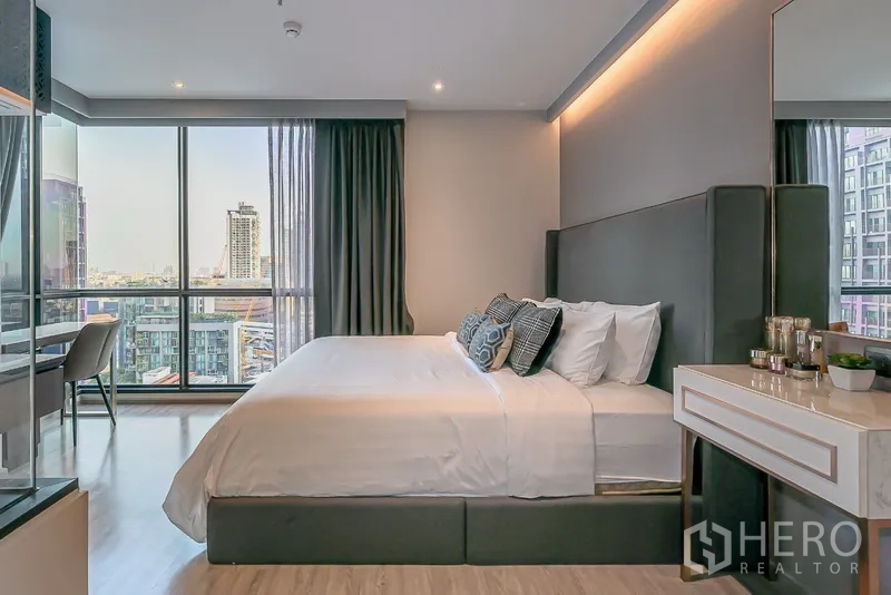 Condominium for rent in Watthana, Bangkok - Master bedroom side view with king bed, study desk by window, and skyline outlook.