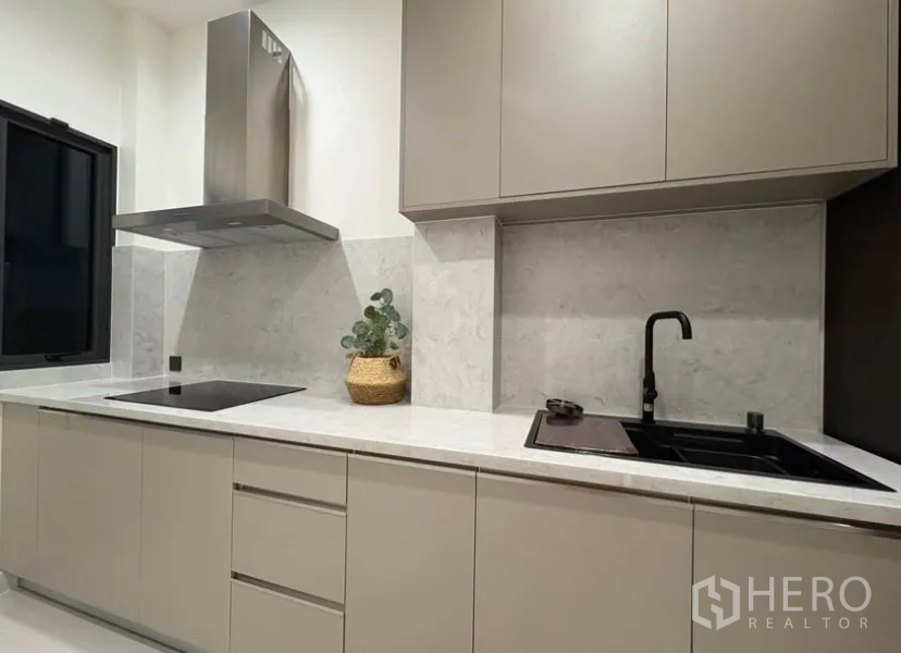 Detached House for rent in Suan Luang, Bangkok - Separate Thai kitchen with stone countertops, induction hob, range hood and black sink.