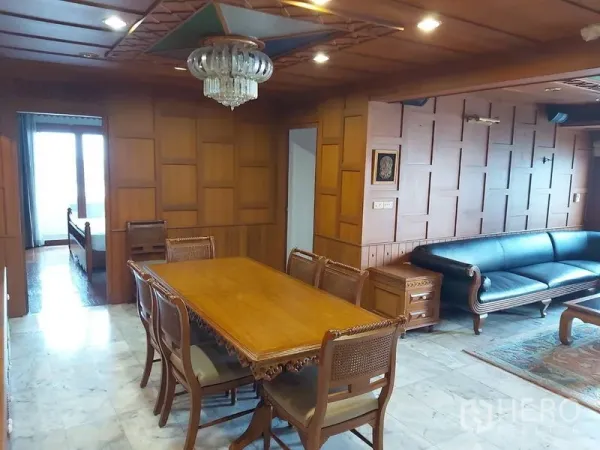 Condominium for rent in Samphanthawong, Bangkok - Wood‑paneled dining room with chandelier, carved table set, and adjacent living area with sofa.