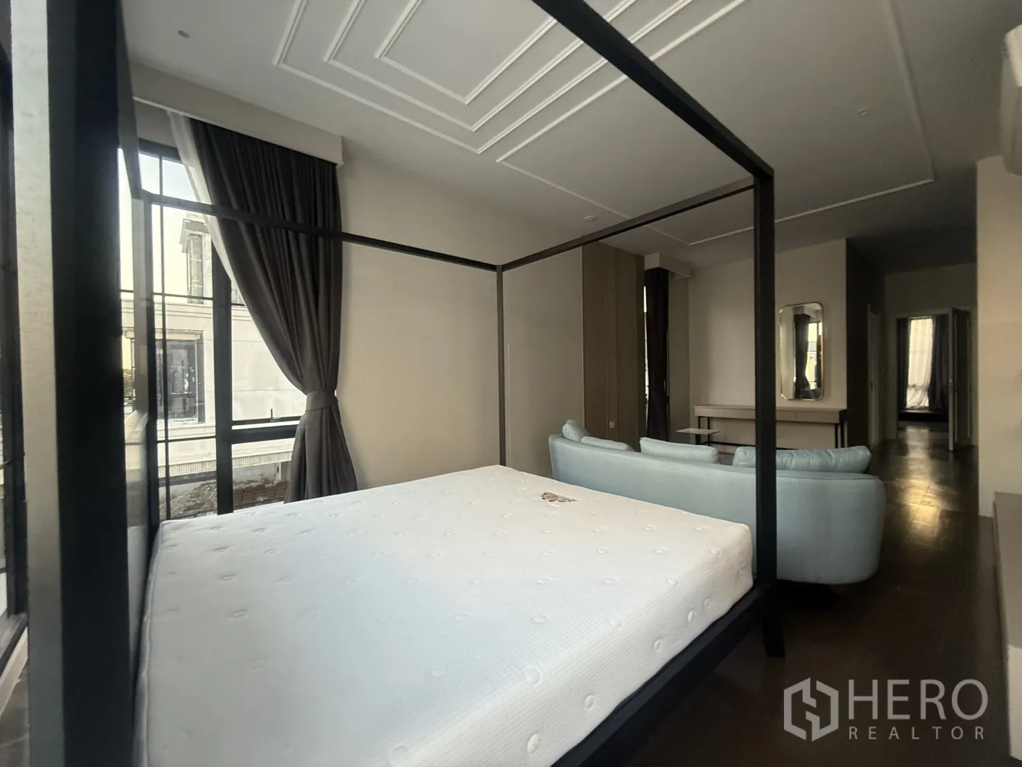 Detached House for rent in Saphan Sung, Bangkok - Bedroom with four-poster bed and cozy sofa seating by corner windows.